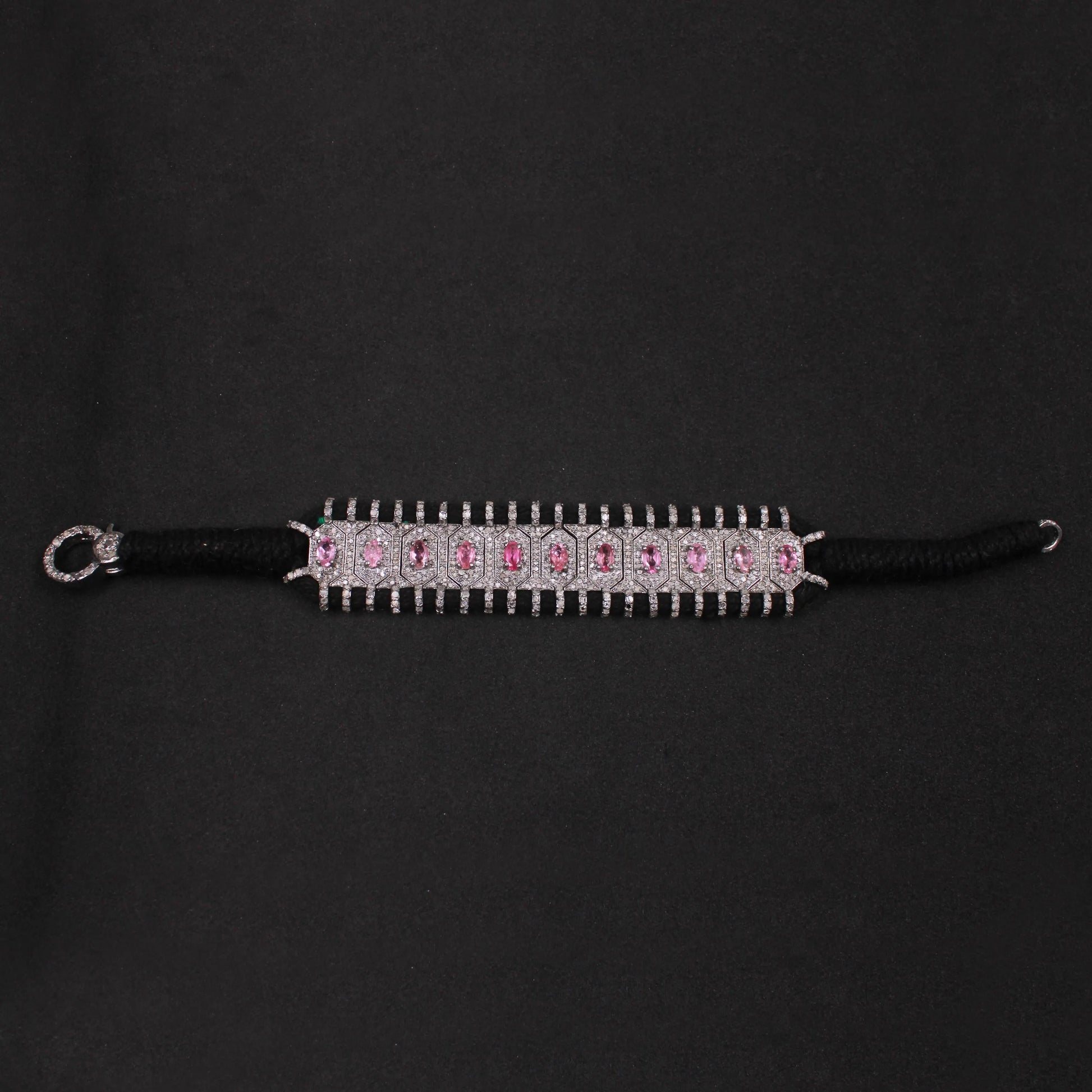 Black hair tie with pink gemstones on a black background