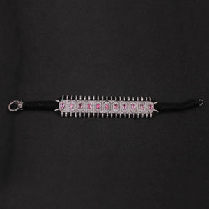 Black hair tie with pink gemstones on a black background